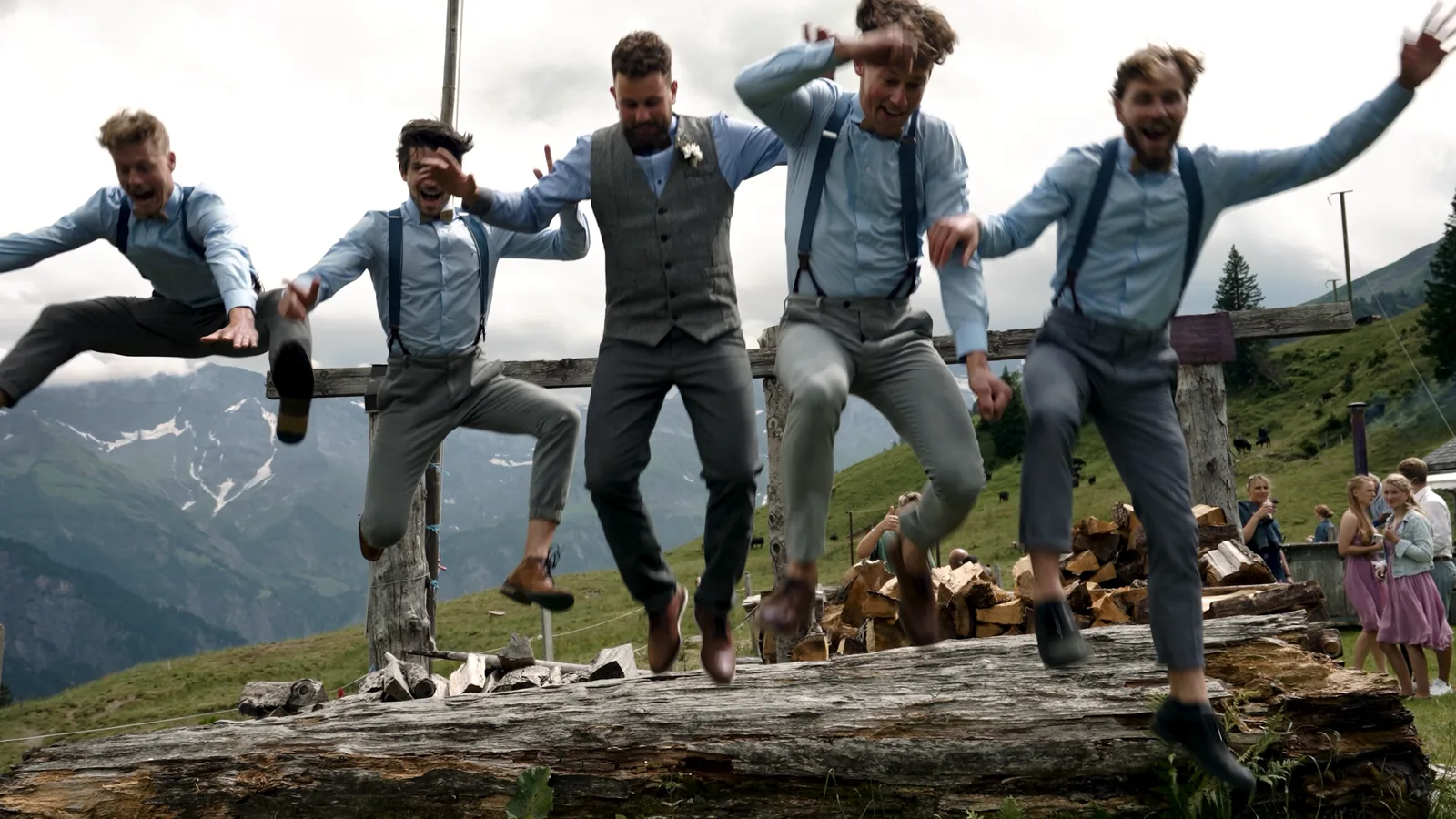 Der Bräutigam springt mit seinen Freunden von einem Baumstamm, Berghochzeit in den Alpen