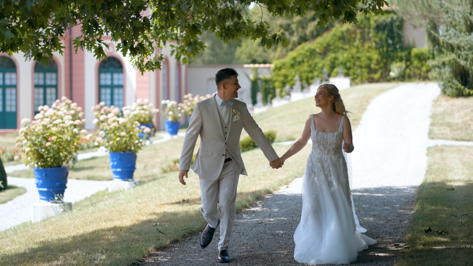 Brautpaar Hand in Hand unter alten Platanen im Schlosspark
